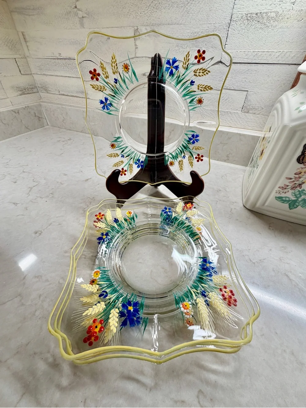 7 1/4” CLEAR GLASS PLATES WITH A COLORFUL, HAND-PAINTED DESIGN & YELLOW TRIM.